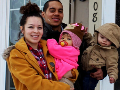 family standing outside their front door in winter coats.
