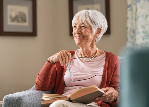 Older woman with short white hair holding glasses and book