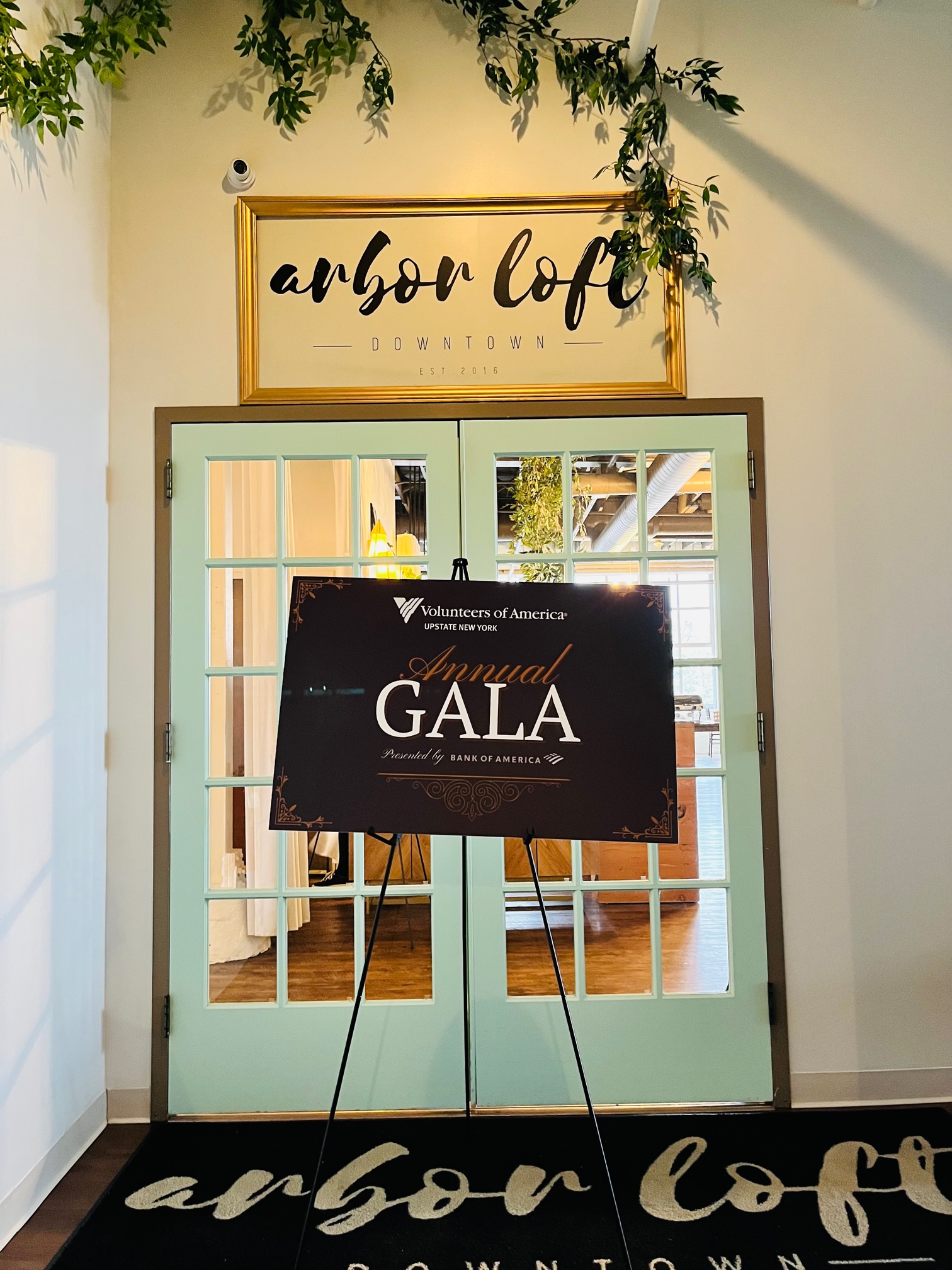 Poster that reads Volunteers of America Annual Gala sits on an easel in front of the entrance to the Arbor Loft event space.