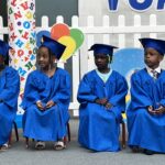 Preschool children in blue graduation robes and hats celebrate their preschool moving up ceremony.