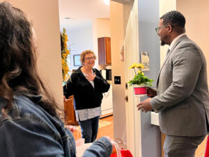 Older woman opens door to surprise flowers being delivered for Mother's Day.