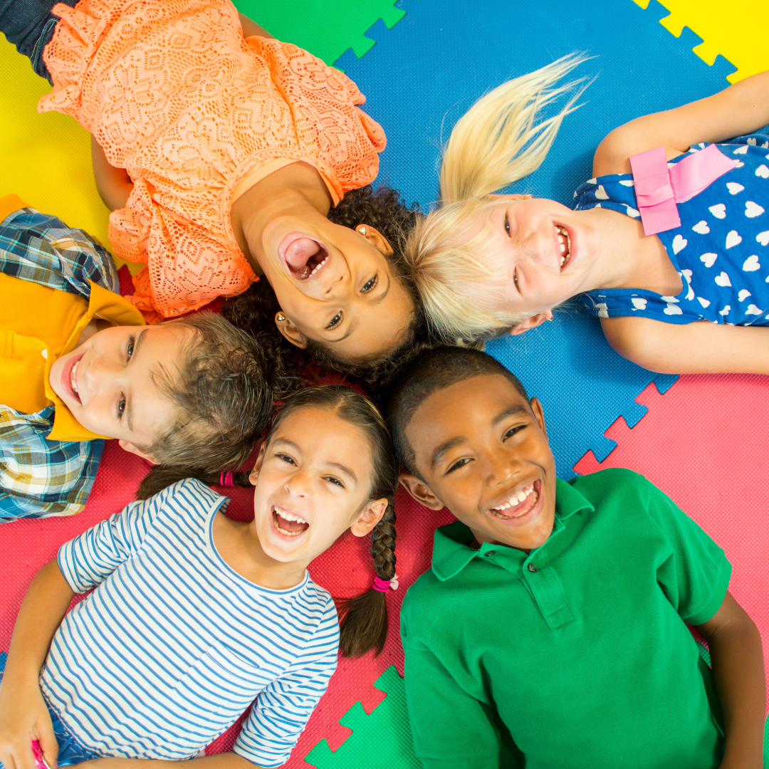 kids laying on the floor in a circle laughing and smiling