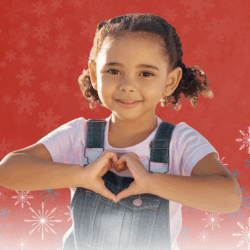 Young girl holds her hands in the shape of a heart.