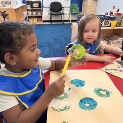 Two pre-school age girls paint with foam letters.