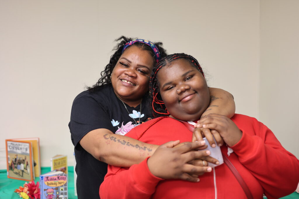 Woman hugs her teenage daughter and both are smilling