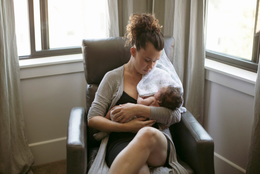 Woman sits in chair cradling an infant baby.