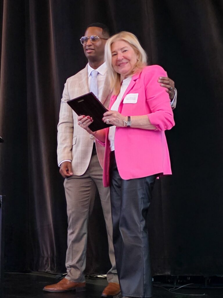 Kitty Van Bortel stands with Dr. Junior Dillion receiving an award